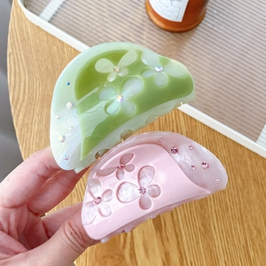 Large acetate flower hair claws in pink and green with rhinestones on a tray