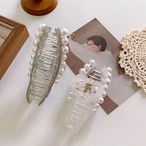 Elegant fishtail hair claws in grey and clear acrylic with white pearls on a lace mat