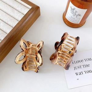 Elegant gold hollow butterfly hair claw clips with amber acrylic texture on white desk