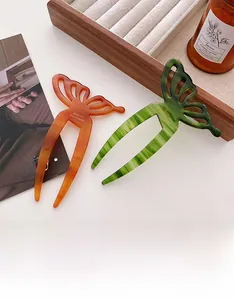 Detail of amber and green acetate hair forks with hollow butterfly design on wooden box