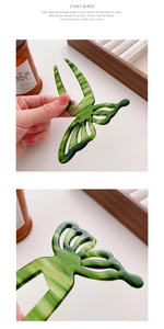Close-up of emerald green hollow butterfly U-shaped hair pin with marble texture