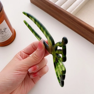 U-shaped hair pin with green marble pattern and cutout butterfly design held in hand