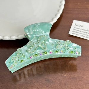 Detail of mint green marble acetate hair claw with butterfly rhinestone embellishments