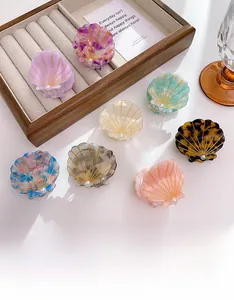 Detail view of shell-shaped acetate hair clips with pearls in various elegant colors