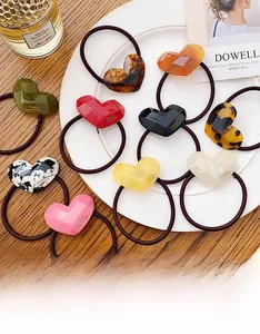 Detailed view of candy-colored acetate heart hair ties in a luxury porcelain display tray