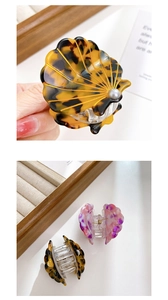 Detail of shell-shaped acetate hair clips with pearl accents in amber and purple floral