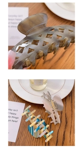 Close-up of three acetate hair claws in hollow grid and marble patterns on wooden surface