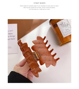 Détail d'une grande pince à cheveux en acétate avec texture ambrée marbrée et ressort métal