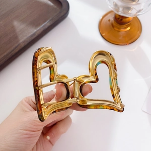 Elegant heart-shaped tortoiseshell hair claw clip with golden metal accents for women