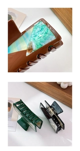 Macro detail of large square hair claws with shell texture inlay and resin finish