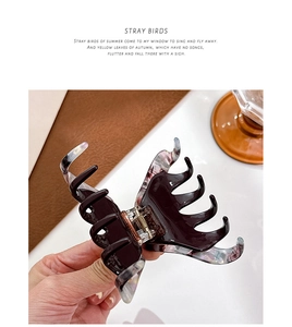 Detail of large marble patterned hair claw clip showing polished acetate texture and grip