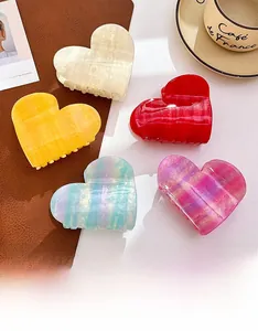 Acetate heart claw clips in multiple colors with pearlescent finish on a marble background