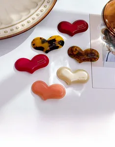 Detailed view of six assorted heart-shaped acetate hair clips with various elegant patterns