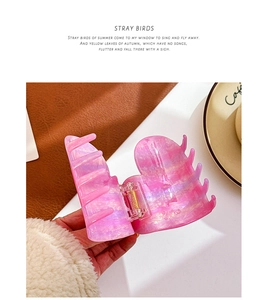 Detail of pink marble acetate heart hair claw clip with golden metal spring closure