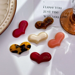 Elegant heart-shaped acetate hair clips in multiple colors on a vintage desktop