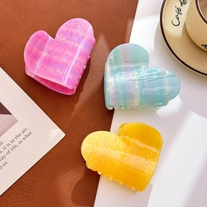 Three elegant heart-shaped acetate hair claws in pink, sky blue, and ginger yellow