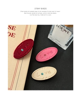 Close-up of retro oval hair clips featuring embossed Love letters and sparkling rhinestones