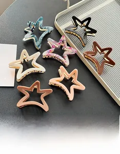 Flat lay view of star-shaped acetate hair claws in various colors on a dark textured surface