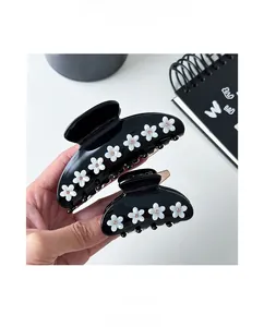 Macro shot of large black acetate hair claw clips with white crystal floral details