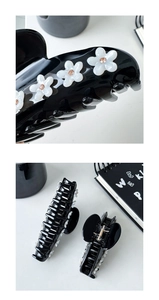 Detail of black resin hair claw clips with white flower and champagne rhinestones