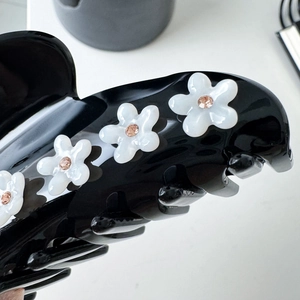 Elegant black acetate hair claw clip with white shell-textured flowers and pink rhinestones