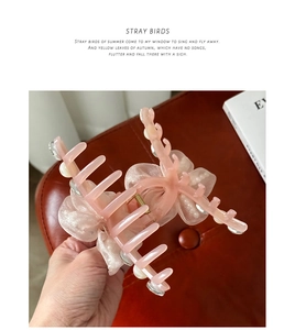 Détail d'une grande pince à cheveux rose avec nœuds en organza et perles pour coiffure