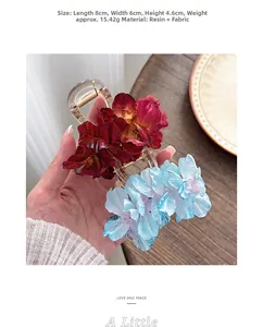 Close-up of elegant red and blue fabric camellia flower hair clips with resin base details