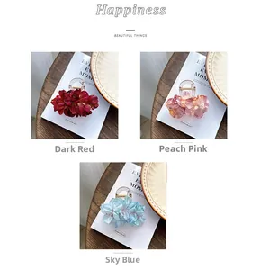 Detail view of satin camellia flower hair clips in dark red, peach pink, and sky blue