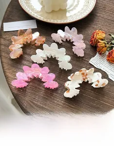Detail of five assorted colorful acetate hair claws on a vintage wooden table setting