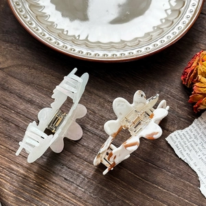 Chic acetate flower claw clips set with marble patterns and green pearl finish on wood