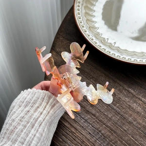 Iridescent pink acetate claw clip with a wavy design and golden metal spring