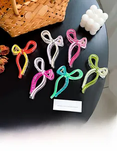 Detailed macro view of acetate bow hair claws in six vibrant colors on a black table