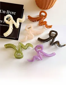 Set of six large wavy hair claws in Morandi colors displayed with artistic props