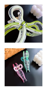 Close-up of lime green and pink acrylic bow hair claws with metal spring details