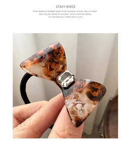 Detailed macro view of tortoiseshell acetate bow hair tie with rectangular crystal