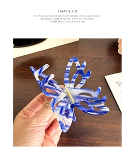Détail de la pince à cheveux papillon marbré bleu et blanc avec ressort doré robuste