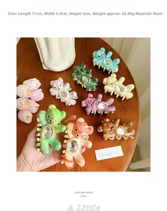 Close-up of resin bear hair claws with embedded rhinestones on a wooden table