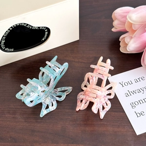 Pinces à cheveux papillon en acétate marbré bleu et rose sur une table en bois