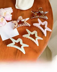 Star-shaped acetate hair claw clips in marble and tortoiseshell patterns on wooden table