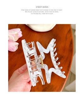 Macro detail of large acetate star hair claw clip with checkered marble pattern in hand
