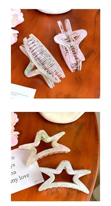 Detailed close-up of large acetate star hair claws showing pearlescent texture and finish