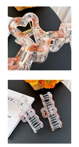 Close-up of three clear acrylic hair claws with embedded pink and orange crushed stones