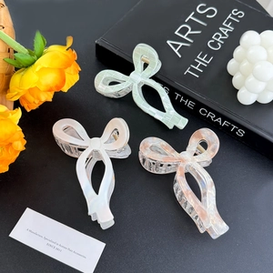 Three acetate bow hair claws in mint plaid, pearl white, and pink marble finishes