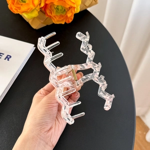 Large wavy transparent acrylic hair claw clip with golden spring held by hand