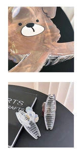 Macro di molletta per capelli con orso e clip iridescente su sfondo libro d'arte