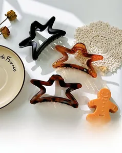 Trois pinces à cheveux en forme d'étoile noires et écaille sur une assiette blanche