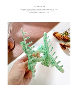 Detail of green floral acetate hair claw clip held by hand for elegant hairstyling