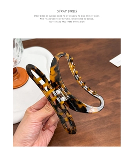 Close-up of a large amber tortoise shell hair claw clip held by hand for daily hairstyling