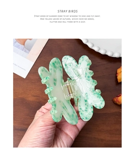 Detailed view of acetate hair claw clip with green marble texture on wooden desk