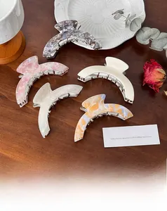Close-up of five acetate geometric hair claws in various marbled patterns on a wood surface